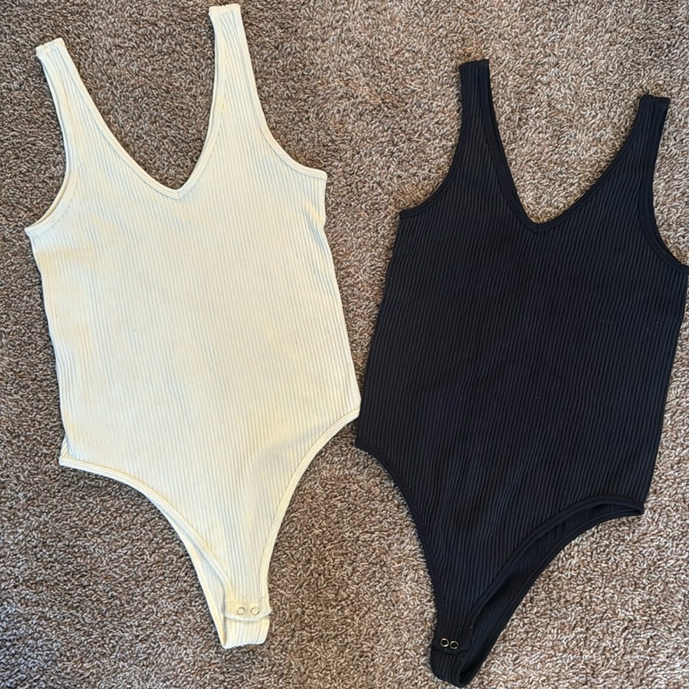 A set of S/M, Gypsy and Rose Bodysuits, one charcoal grey and the other crème.